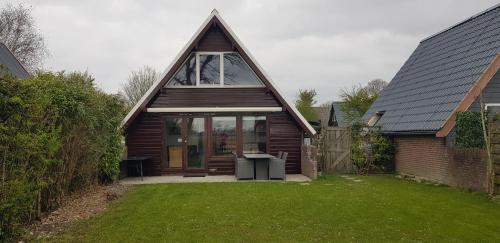 a small house with a large window in a yard at De Weide Blick in Tuitjenhorn
