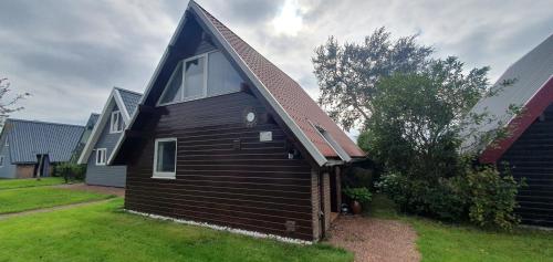 a small black house with a gambrel roof at De Weide Blick in Tuitjenhorn