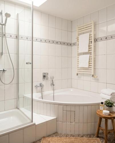 a white bathroom with a tub and a shower at Stilvolles Apartment mit Wintergarten, Balkon & Parkblick - VILLA KAETHE am Kurpark in Warnemünde