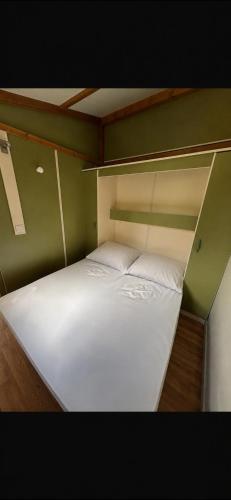 a large white bed in a green room at Chalet en Corse in Santa-Maria-Figaniella