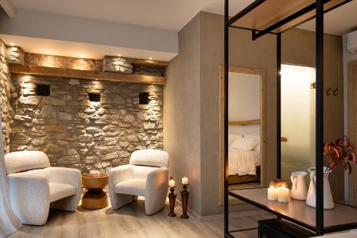 a room with two white chairs and a stone wall at Evoras Boutique Hotel in Xirokámbion