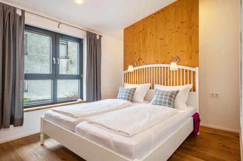 a bedroom with a bed with a wooden headboard and a window at Wohnplatz 52 in Inzigkofen