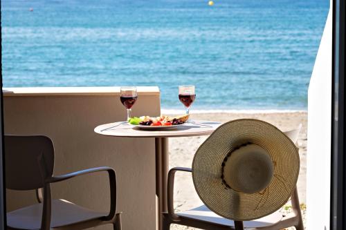 a table with two glasses of wine and a plate of fruit on the beach at Fodele Beachfront Apts in Fodele