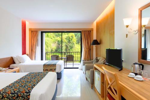 ein Hotelzimmer mit zwei Betten und einem Fernseher in der Unterkunft Tinidee Golf Resort Phuket in Kathu