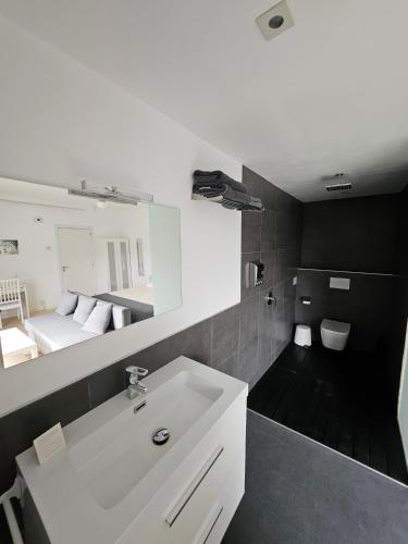 a bathroom with a white sink and a bedroom at Jingtu Wellness & Spa Resort in Comares
