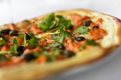 a pizza with black olives and greens on it at Wildes Inns in Chesterfield