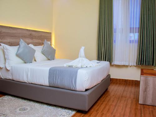 a bedroom with a large bed with white sheets at Amanda Resort in Kakamega