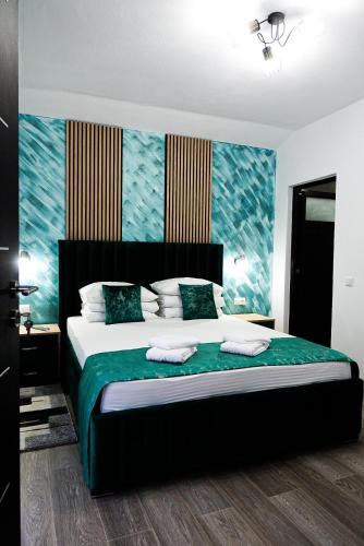 a bedroom with a large bed with a green blanket at Dey Villa, Valea Avrigului, Transilvania in Avrig