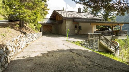 a house with a stone wall and a driveway at Chalet authentique à Ovronnaz in Leytron