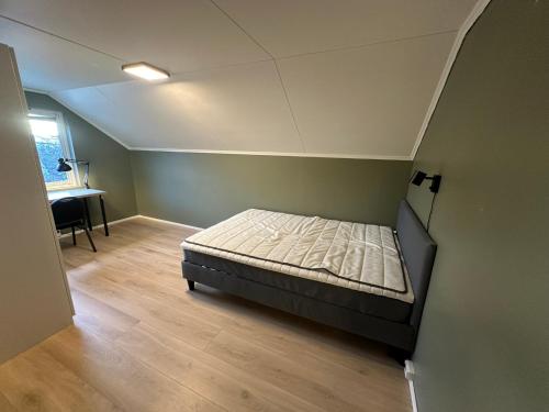 a small bedroom with a bed and a desk at Flott sommerhus midt i Lillehammer sentrum in Lillehammer