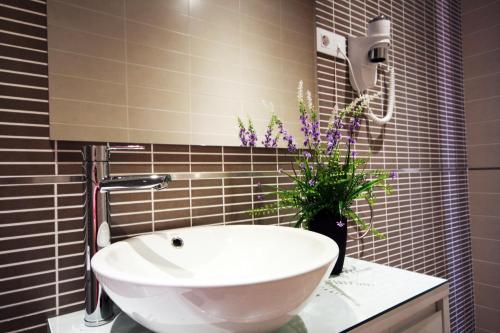 a bathroom with a white sink and a vase of flowers at Noa Apartment in Madrid