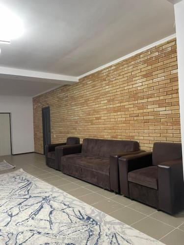 a living room with couches and a brick wall at Laguna City Lux in Tegirmenty