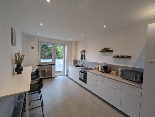 a kitchen with white cabinets and a large window at HarmoNest 2 Mgladbach south in Mönchengladbach