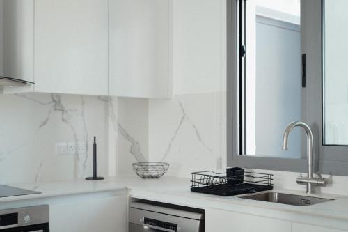 a kitchen with white cabinets and a sink at Coral Bay Garden in Peyia