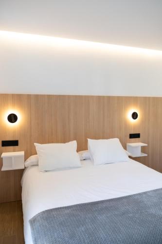 a bedroom with a white bed with white pillows at Apartamentos Don Tomás in Jaén