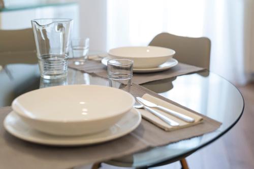 a glass table with white plates and glasses on it at TorinoToStay Apartments in Turin