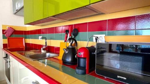 a colorful kitchen with a sink and a microwave at Vila Nadja SEAFRONT in Bar