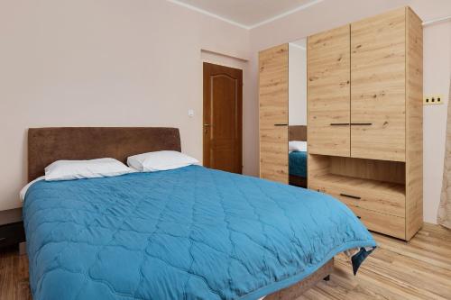 a bedroom with a blue bed and a wooden cabinet at Maslina Krtoli in Tivat