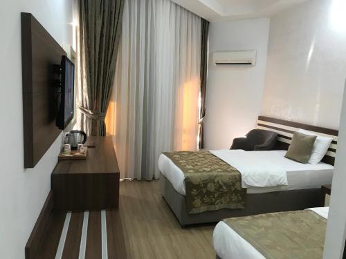 a hotel room with two beds and a flat screen tv at Olbia Hotel in Antalya