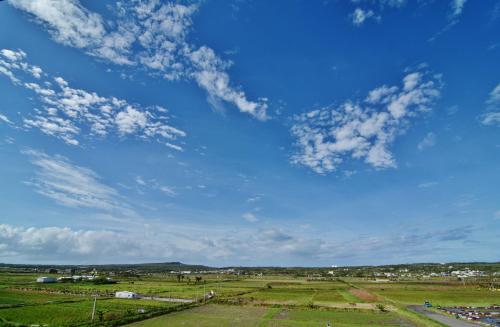 a blue sky with clouds over a green field at Mulin B&B in Hengchun