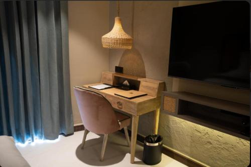 a desk with a chair in a room with a television at Pixcel Holidays in Calangute