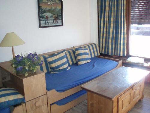 a living room with a blue couch and a table at Le Bec Rouge in Tignes