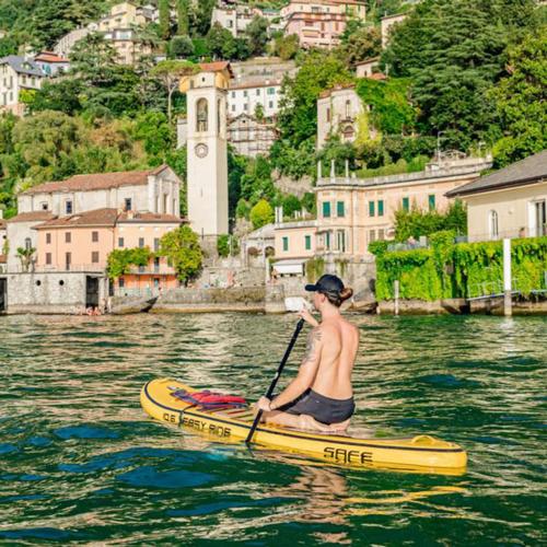 a man sitting on a paddle board in the water at LA CALETTA SUITE APARTMENT- Panoramic Shared Pool, Secured Parking, Water Activities in Blevio