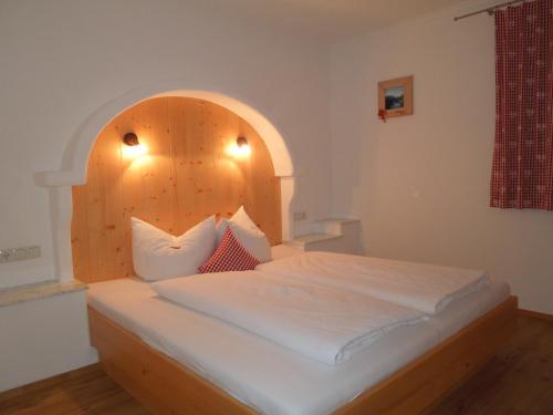 Schlafzimmer mit einem Bett mit einem Kopfteil aus Holz in der Unterkunft Haus Panoramablick in Zellberg
