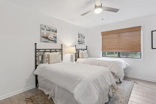 two beds in a white bedroom with a ceiling fan at Harbour Oaks, Unit 413 in Saint Simons Island