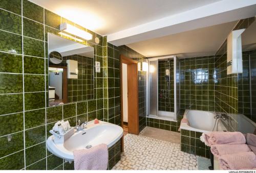 a green tiled bathroom with a sink and a tub at BeiArnold in Schleiden