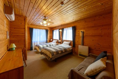 ein Schlafzimmer mit zwei Betten in einer Blockhütte in der Unterkunft Madarao Vacances Village in Iiyama