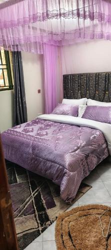 a bedroom with a purple bed with a canopy at Sylvan hotel in Kasangati