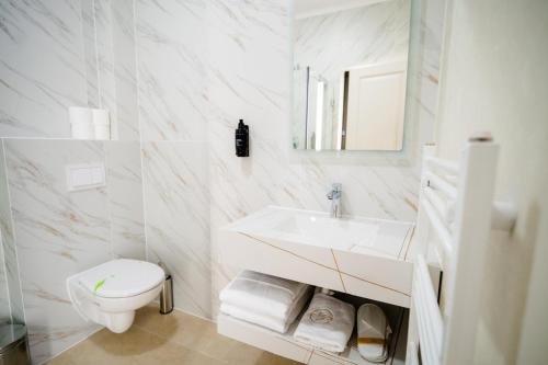 a white bathroom with a sink and a toilet at Leo Resort and Spa in Petrova