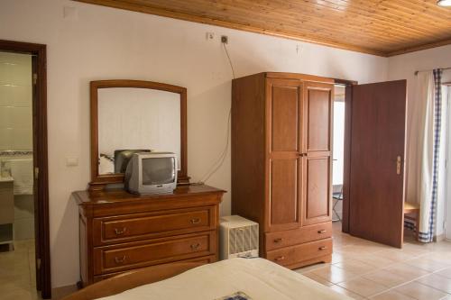 a bedroom with a dresser with a tv and a mirror at D. Antonia in Peniche