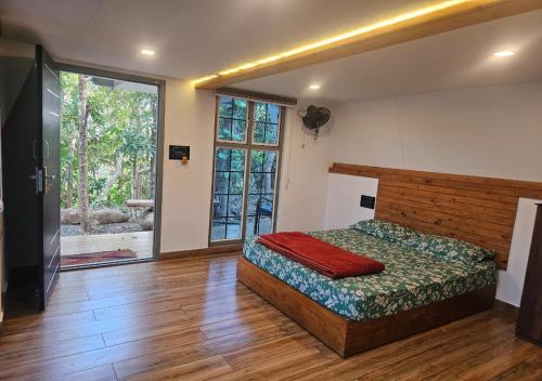 a bedroom with a bed and a large window at Poomala Holiday Village in Mulagunnathukāvu