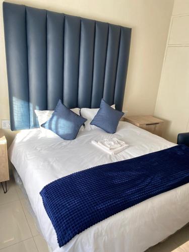 a large bed with a blue headboard and blue pillows at Nvivi boutique hotel in Polokwane