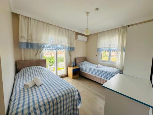a room with two beds and a table and two windows at Evalacati - Villa Harnup- Detached house with private pool and garden in Alaçatı