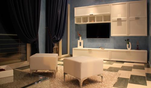 uma sala de estar com duas cadeiras brancas e uma televisão em Central Rooms em Noto Marina