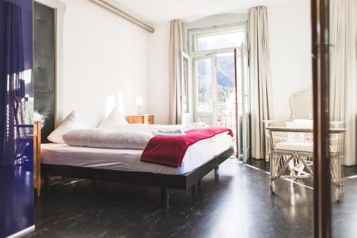 Un dormitorio con una cama con una manta roja. en Kurhaus Bergün, en Bergün