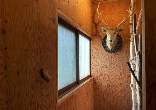 a room with a deer head on the wall with a window at SappoLodge in Sapporo
