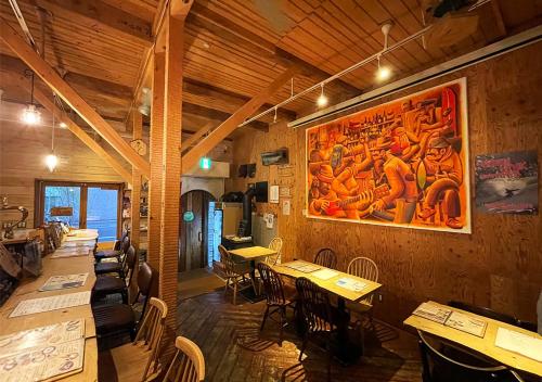 a restaurant with tables and chairs and a large painting on the wall at SappoLodge in Sapporo