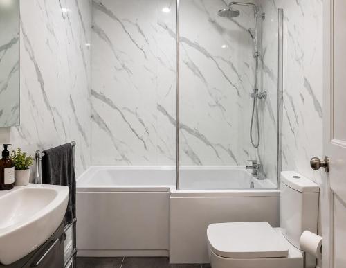 a bathroom with a tub and a toilet and a sink at Coastal charm in Herne Bay