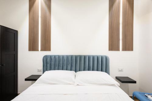 a bed with a blue headboard in a room at Azzurra Rooms Suite in Battipaglia