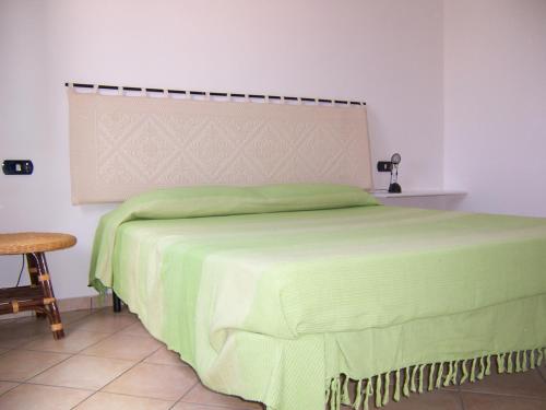 トッレ・デイ・コルサリにあるCasa Vacanza Marina di Arbusのテーブルと椅子が備わる客室の緑のベッド1台分です。