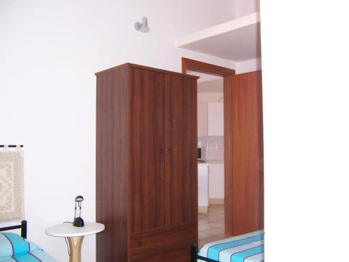 トッレ・デイ・コルサリにあるCasa Vacanza Marina di Arbusのベッドの横に木製キャビネットが備わるベッドルーム1室が備わります。