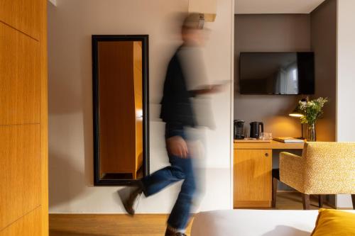 Eine Person, die einen Raum mit einem Spiegel betritt in der Unterkunft Hotel Le Six in Paris
