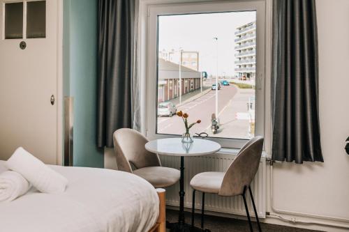 a hotel room with a bed and a table and a window at Divi Divi Zandvoort in Zandvoort