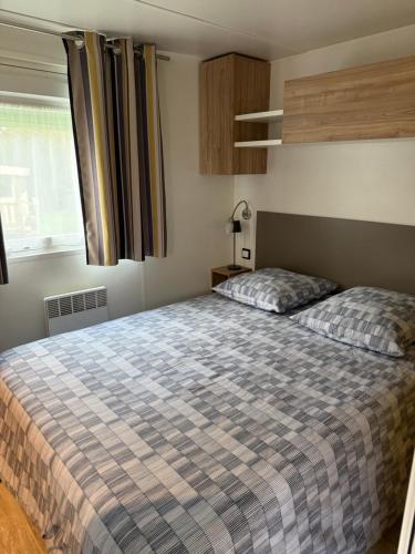 a bedroom with a bed with a checkered blanket at Mobil home 459 in Pont-Aven