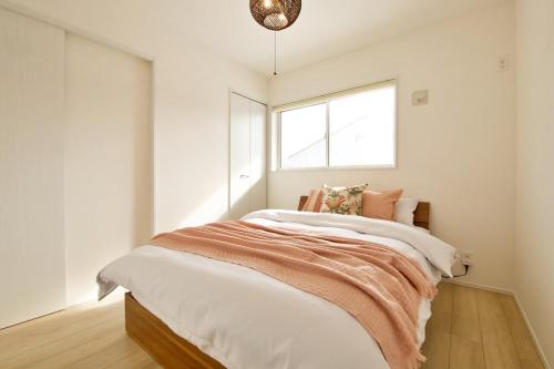 a bedroom with a bed with white walls and a window at Dual Residence Nakijin A in Koechi