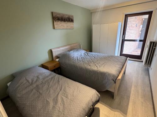 a bedroom with two beds and a window at Casa Ghentele in Blankenberge